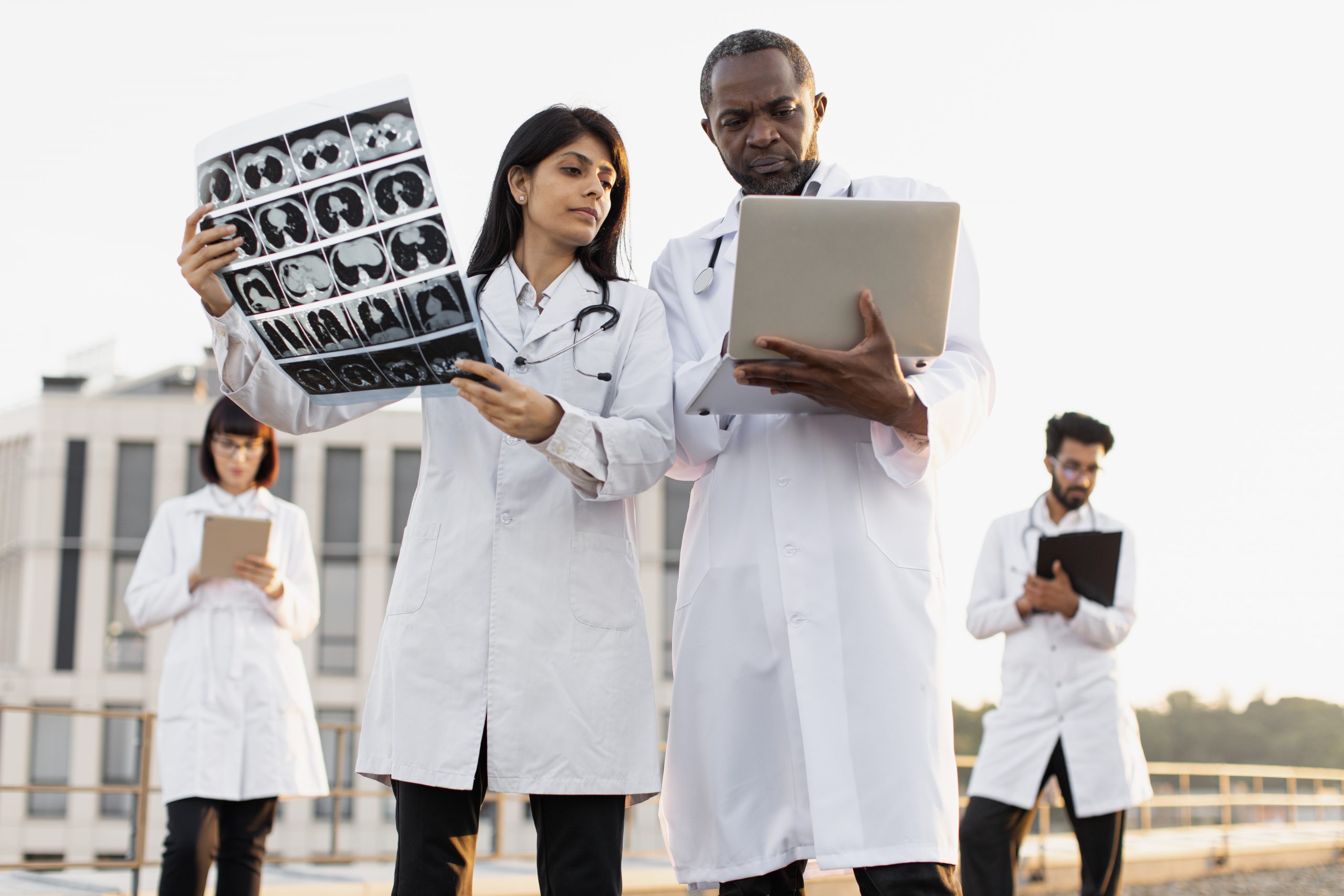 Experienced medical workers talking about patient examination results. Portrait of male and female doctor with stethoscope smiling on roof